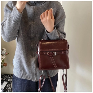 Detail view of a vintage dark red handbag held by a model in a cozy winter setting