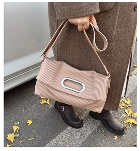 Detail of light pink pleated bag featuring a silver oval metal buckle and wide shoulder strap