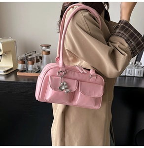 Detail of pink faux leather shoulder bag with silver heart pendant and front pockets