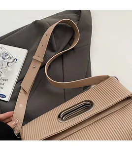 Close-up of pleated beige faux leather shoulder bag with silver oval metal hardware