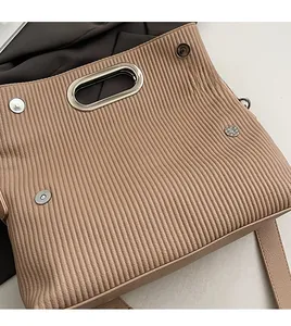 Detail of light khaki pleated leather handbag with metal handle and magnetic snap