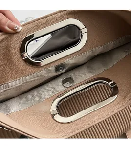 Detail of silver oval handle and magnetic closure on pleated brown leather tote