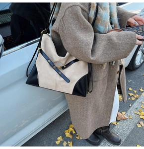 On-body view of large beige and black crossbody bag in an outdoor street scene
