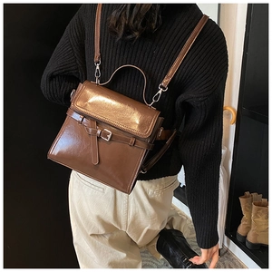 Detail eines dunkelbraunen Vintage-Rucksacks aus Kunstleder mit Metallschnalle und Glanz