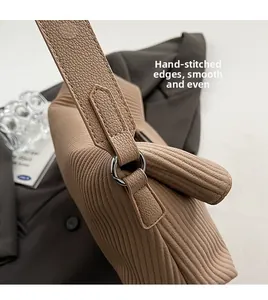 Detail of caramel pleated bag showing fine stitching and silver ring hardware
