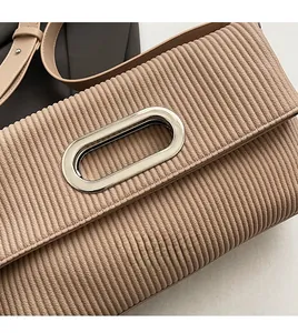 Detail of beige pleated fabric texture with a large oval silver metal buckle on bag