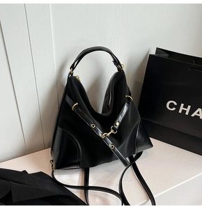 Close-up of black nylon tote bag with leather piping and gold metal zipper detail