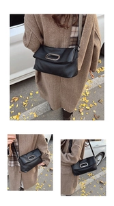 Detail of black pleated shoulder bag featuring a large silver oval metal buckle on flap