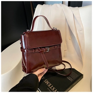 Detailaufnahme einer weinroten Lackledertasche mit eleganter Schnalle und Riemen