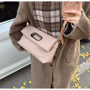 Detail of light beige pleated crossbody bag featuring a silver buckle and braided strap