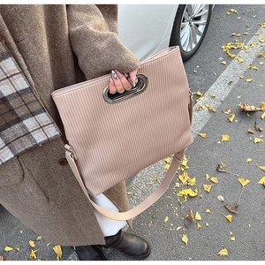 Detail of pink corduroy shoulder bag with metal cutout handle and leather strap