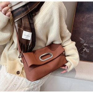 Detail of caramel pleated shoulder bag with oval metal buckle on autumn knitwear