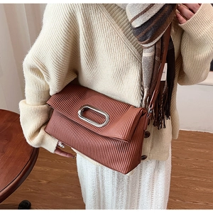 Elegant caramel pleated shoulder bag with oval silver buckle shown in a lifestyle setting