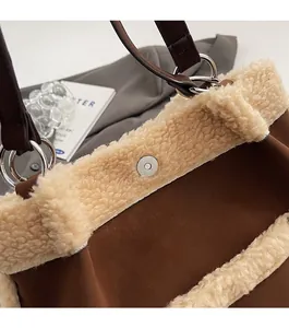 Close-up of faux shearling stitching detail and magnetic clasp on brown suede tote bag