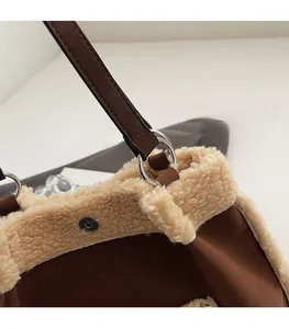 Detail of magnetic buckle, silver metal rings and plush faux shearling trim on brown bag