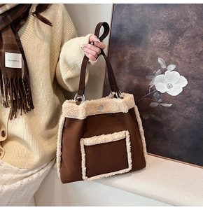 Close-up of winter faux shearling trim on a brown suede tote bag held by a model