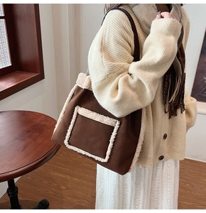 Brown suede tote bag with faux shearling trim and plush pocket shown on woman's shoulder