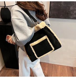 Detail of a large black tote bag with plush beige trim and metal ring shoulder strap