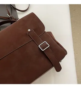 Close-up of brown suede backpack detail with silver buckle and refined stitching