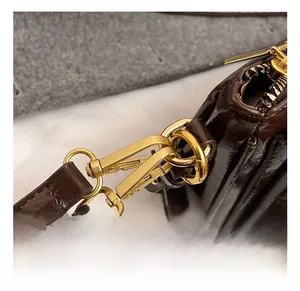Close-up of golden metal spring hook and double stitching on dark brown leather bag