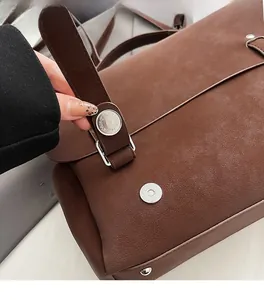 Detail view of the secure silver magnetic clasp on a brown leather commuter backpack