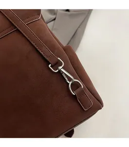 Macro shot of silver metal hooks and fine stitching on brown frosted leather tote bag