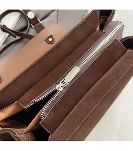 Detail view of smooth metal zipper and layered interior of dark brown matte tote bag