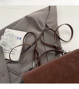Detail of slim dark brown straps and silver metal buckles on a matte shoulder bag