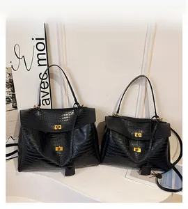 Detail of black crocodile texture handbag with golden clasp lock and matching leather tag