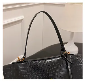 Detail of black crocodile texture leather surface and gold buckle on a tote bag