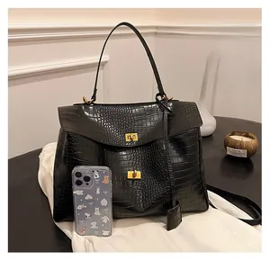 Detail showing crocodile texture leather on large black handbag with gold clasp