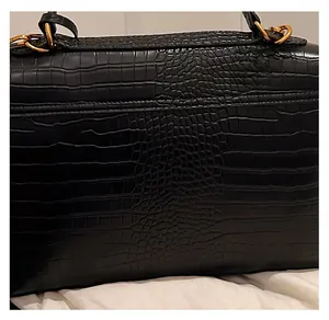 Close-up of black crocodile embossed leather texture with elegant golden metal hardware