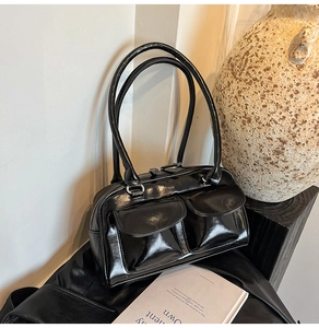 Detail of black glossy shoulder bag with dual front flap pockets and leather finish