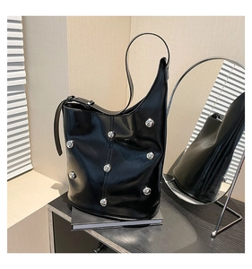 Detail of glossy black leather bucket bag with silver metal rivets and adjustable strap buckle
