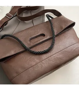 Gros plan du sac cabas en cuir marron avec poignée en corde torsadée et bandoulière en toile