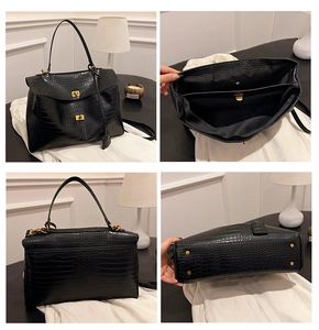 Detail view of black crocodile pattern tote with gold metal buckle and protective bottom feet