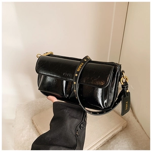 Detailed shot of black patent leather underarm bag with gold buckles and Paris logo