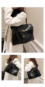 Detail of black crocodile texture tote bag with golden twist-lock buckle and flap closure