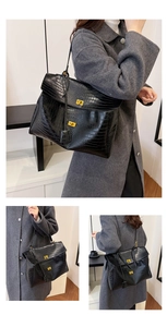 Detail shot of black crocodile texture handbag with dual golden twist locks and large capacity