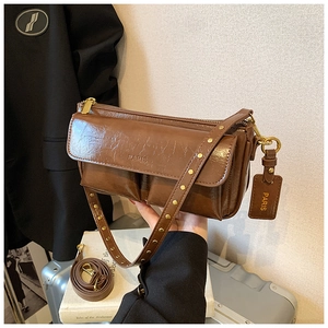 Detail of dark brown vintage faux leather crossbody bag with dual pockets and Paris logo