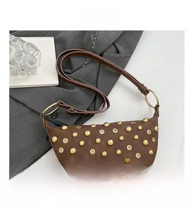 Vue detaillee du sac demi-lune marron fonce avec rivets dores et oeillets metalliques