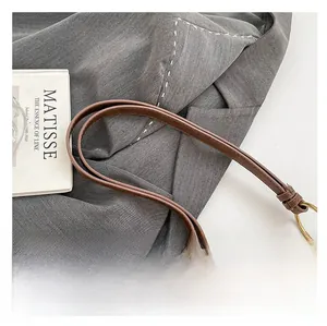 Détail de la bandoulière en cuir marron avec coutures renforcées et rivets dorés vintage