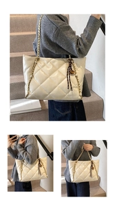 Detail of cream quilted tote bag featuring chain straps and a decorative bell charm