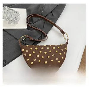Sac demi-lune marron avec rivets dorés et smartphone pour comparer la taille