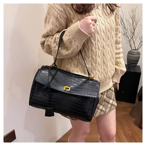Detail shot of black crocodile embossed tote bag with gold twist lock on knit sweater