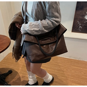 Gros plan sur la texture en cuir souple marron foncé et la poignée en corde noire torsadée