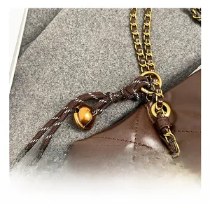 Close-up of dark brown quilted leather tote bag with gold chain and bell charm