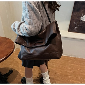 Détail d'un grand sac cabas marron foncé avec cordelette noire et texture cuir souple