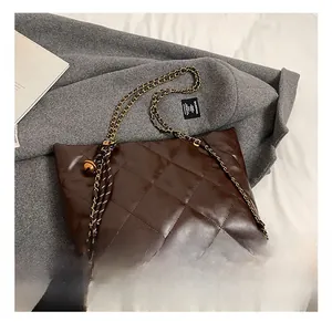 Detail of dark brown quilted faux leather tote bag with elegant golden chain strap