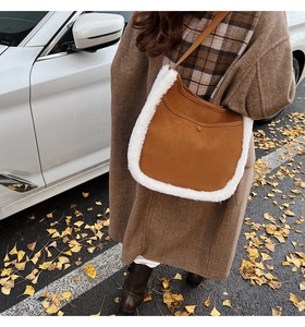 Close-up of autumn brown suede bucket bag with white faux fur trim on ginkgo leaf background